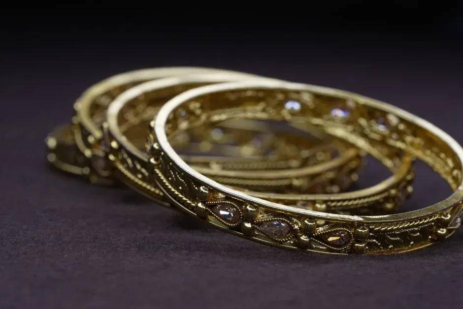 Detailed gold bangles on a dark surface