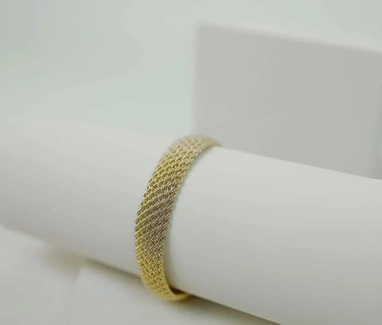 Textured gold bracelet on a display cushion