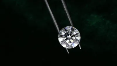 Round faceted diamond held in tweezers