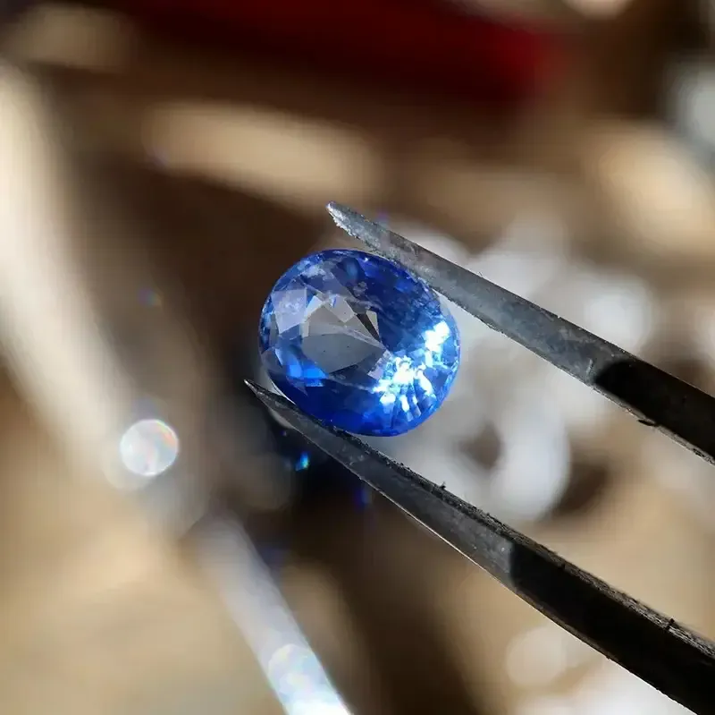 Blue sapphire held in gemstone tweezers