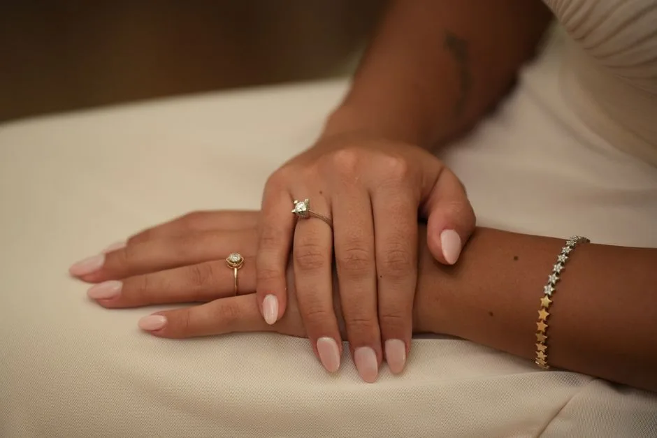 Hands wearing stone-set rings beside a star-shaped link bracelet