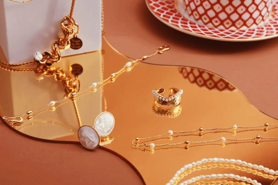 Gold-colored necklaces, rings and pearl-like beads arranged on a mirror