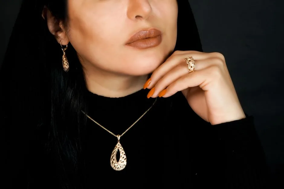 Person wearing a matching gold-colored pendant, earring and ring