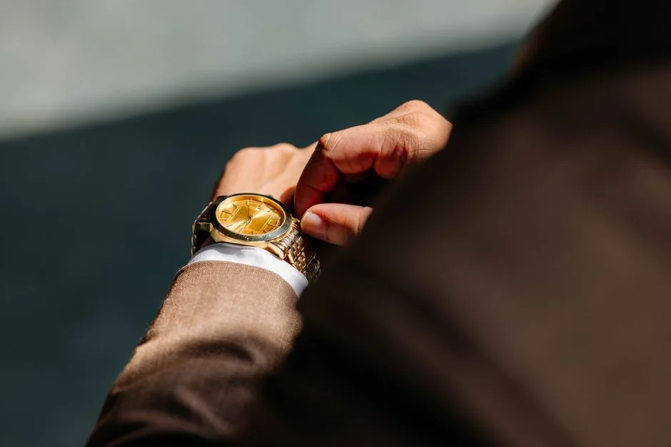 Person adjusting a gold-colored wristwatch with a metal bracelet