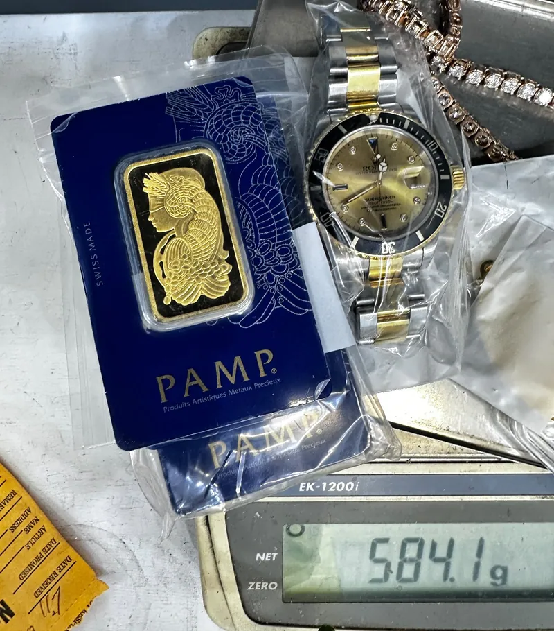 PAMP-branded packaged bar beside a two-tone wristwatch on a metal tray