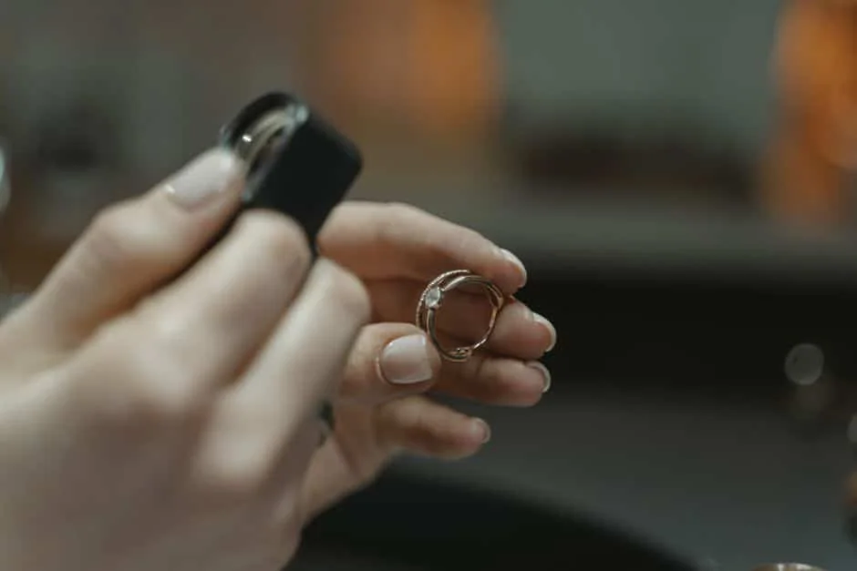 Hands examining a jewelry piece at a jeweler work surface