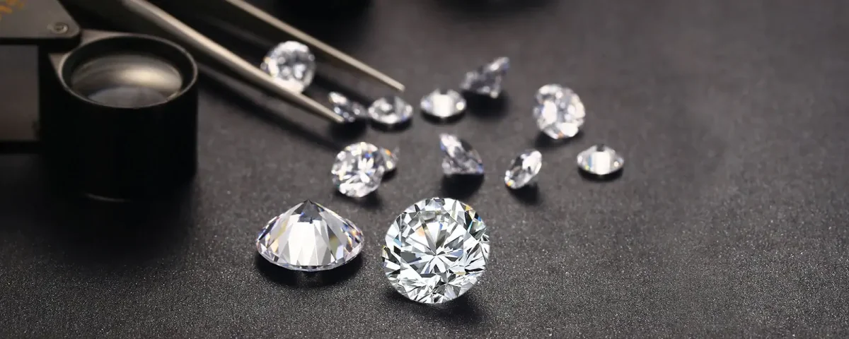 Loose polished diamonds with a jeweler loupe and tweezers